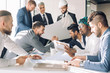 © alfa27 - Multiracial group of constructors, builders, engeneers and architects discussing blueprint at office. All men are dressed in business suits, and white shirts, one of them wears hardhat on head