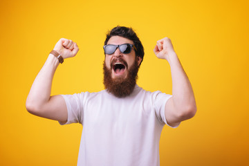 portrait excited bearded man in sunglasses standing with fists up adn screaming