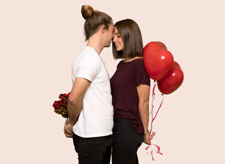 Couple in valentine day holding a heart symbol and balloons over isolated background