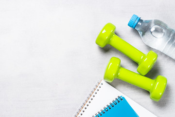 Dumbbells, notepad, water and apple top view. 