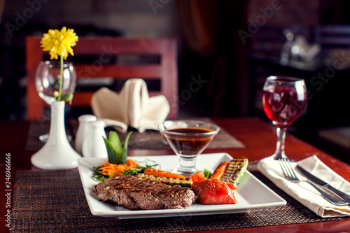 Zdjęcie XXL Stek wołowy z grillowanymi warzywami podany na białym talerzu. Pojęcie żywności
