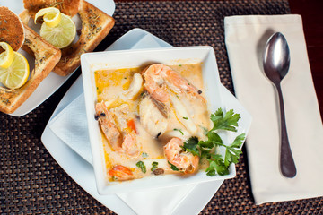 Wall Mural - Seafood cream soup with toasts in white plate on the table. Food and restaurant concept