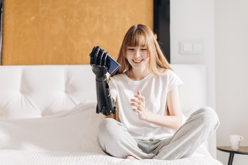 pleasant girl having fun with smartphone, entertainmnet, girl checking her robotic mechanical arm indoors