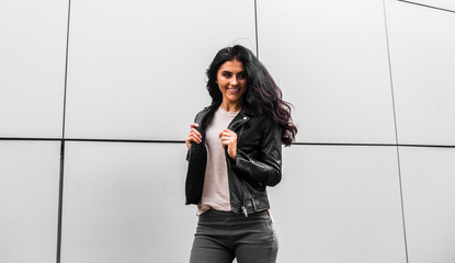 young latin woman walking with happy emotion on grey wall