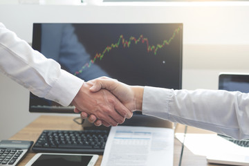 Wall Mural - shaking Hand between businessman of cooperation over Stock market chart, business trading concept.