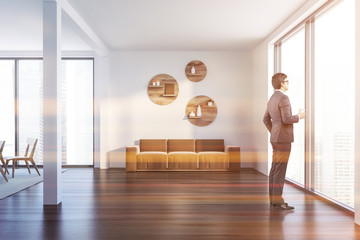 Man in white living room with beige sofa