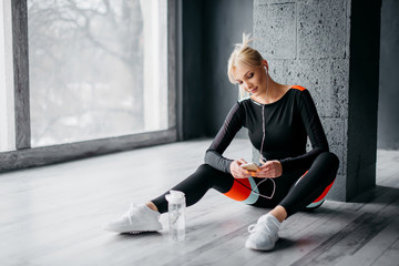 Wall Mural - sports female sits on floor and listens to music