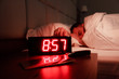 © Тимур Конев - Alarm clock on bedside table with red numbers, kitchen knife, sleeping man in bed in dark room. Concept chef sleeping after hard day at restaurant, sleep disturbance, oversleep work, night shift
