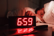 © Тимур Конев - Alarm clock on bedside table with red numbers, kitchen knife, sleeping man in bed in dark room. Concept chef sleeping after hard day at restaurant, sleep disturbance, oversleep work, night shift
