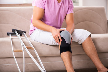 Wall Mural - Young man with injured knee recovering at home