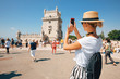 Happy traveler girl in Lisbon near Belem Tower. Tourist woman taking picture of Belem Tower, Portugal