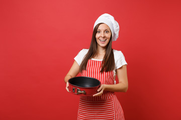 Wall Mural - Housewife female chef cook or baker in striped apron, white t-shirt, toque chefs hat isolated on red wall background. Housekeeper woman holding metal baking form for pie. Mock up copy space concept.