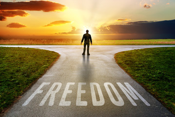 freedom lettering on a path towards a beautiful sunset on the horizon