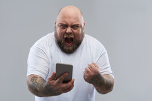 Furious Man Shouting At His Smartphone Against Grey Background