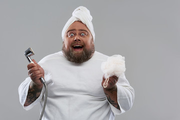 Wall Mural - Waist up of excited man smiling and holding shower head and shower puff