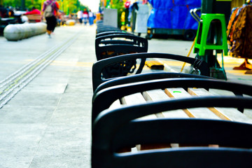 Seating pedestrian bench along shopping district foot path made of steel and wood for old people and children to sit and relax