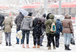 People waiting for public transport at bus stop in heavy blizzard in winter