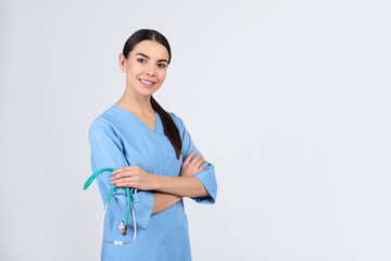 Wall Mural - Portrait of medical assistant with stethoscope on light background. Space for text