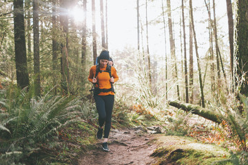 a young woman hiking through the forest with a baby on her back.
