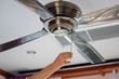 electric irony ceiling fan and woman hand. Ceiling fan indoors in the hotel room. Closeup