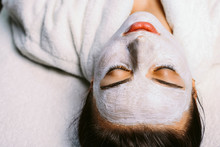 Beautiful Caucasian Girl Resting With Closed Eyes In A Spa Center While On Her Face Is Applied A White Mask In Medical Purposes For Skin Care.