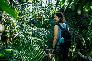 Portrait of young and beautiful lady going away from camera through the tropical garden, Lisbon, Portugal.