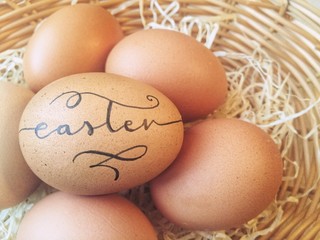 Handlettered eggs in a wicker basket for Easter celebration