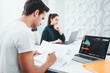 © leonidkos - Two business colleagues working together at modern office and using laptop. Young coworking people team sitting at table and having meeting about new great ideas