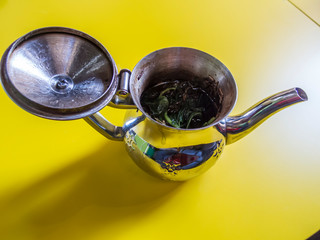 Open Moroccan teapot with black tea and mint 