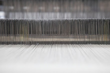 Yarn Thread Lines On The Weaving Loom Machine. A Loom Machine For Clothing Or Woven Label. Weaving Machine For Garment Industry. Weaving Loom In Textile Factory.