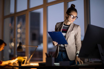 Poster - Young attractive businesswoman bending over workplace while looking at computer screen during work