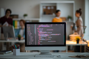 workplace of it-developer or programmer with computer screen with coded data on background of office