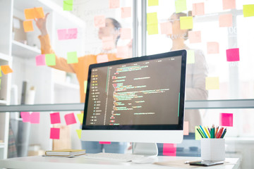 Wall Mural - monitor of computer with coded data and office managers planning work and sticking notes on board on