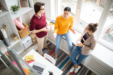 Poster - Young casual colleagues standing by office window and discussing organization moments during coffee break