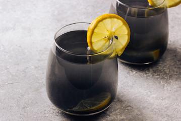 Black lemonade with charcoal and lemon on a light background