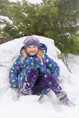 Happy baby on winter background. Portrait of a happy blue-eyed little girl playing in the snow. A 7-year-old girl is having fun playing in the winter Park. The concept of a happy childhood.