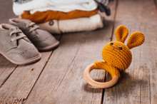 Baby Wooden Toy Bunny Near Baby Booties And Clothes