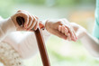 © Photographee.eu - Closeup of elderly lady holding walking cane in one hand and holding volunteer's hand in the other