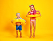 © JenkoAtaman - happy children girl and boy in swimsuit with swimming ring donut on colored yellow background.