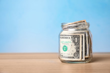 Donation Jar With Money On Table Against Color Background. Space For Text