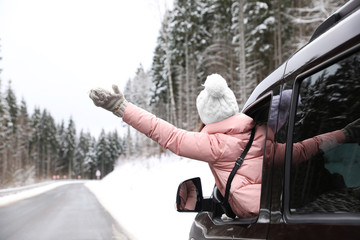 Wall Mural - Young woman looking out of car window on road. Winter vacation