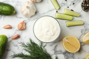 Flat lay composition with cucumber sauce and ingredients on marble background