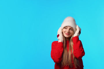 Sticker - Portrait of emotional young woman in stylish hat, sweater and mittens on color background, space for text. Winter atmosphere