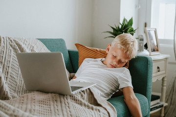 Young boy asleep with his laptop on his tummy