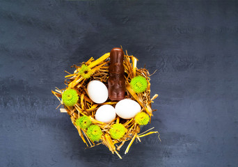 Festive easter background. White eggs with chocolate hare on straw texture with spring flowers. 