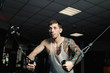 © combo1982 - Handsome athletic man trains pectoral muscles on a block simulator in the gym.