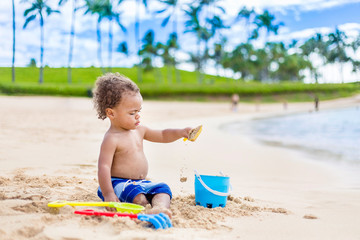 Cute mixed race little boy playing in the sand on a tropical beach vacation. Candid, Full length photo with lots of copy space on a idyllic, scenic beach.