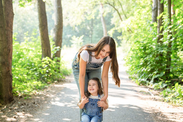 Wall Mural - Family and nature concept - Mother with daughter have fun in the green park