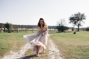 The bride in a delicate pink dress with paillettes on a brown horse. Wedding in the forest at sunset. Walking in the nature near the water.