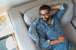 © Rido - Mixed race man relaxing on couch